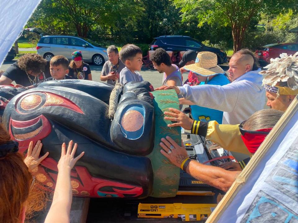 Native and environmental activists place their hands on the totem pole during an interfaith prayer in Haw River aimed at opposing the proposed MVP pipeline.
