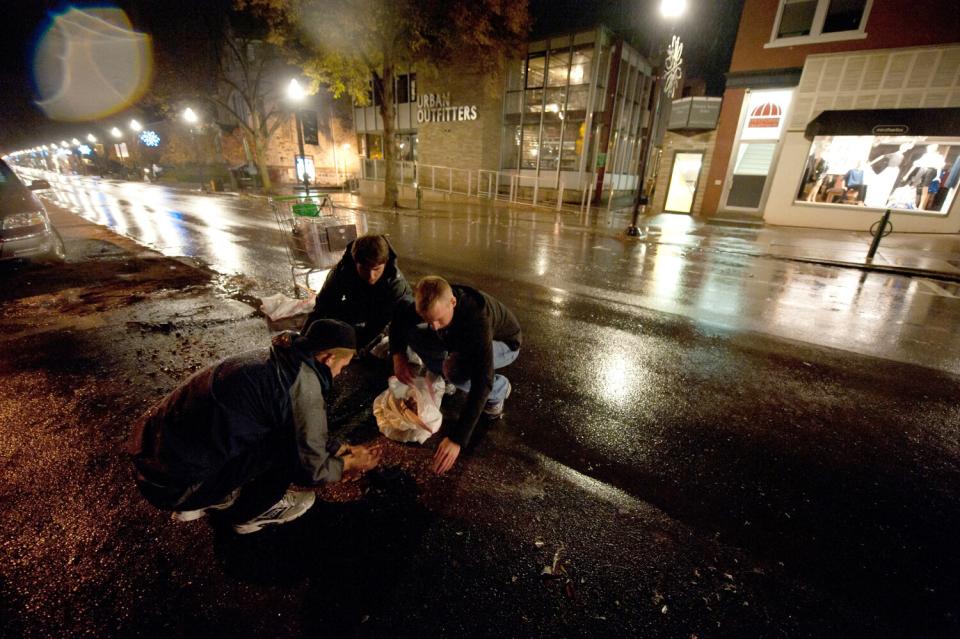 Penn State students Ryan Smith, Brennan Pankiw and Jared Hook clean up broken glass and debris along East College Avenue.