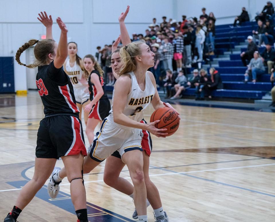 Haslett's Ellie Humble (2) dribbles between two St. Johns players and drives to the basket in District semi-final play Wednesday, March 2, 2022.