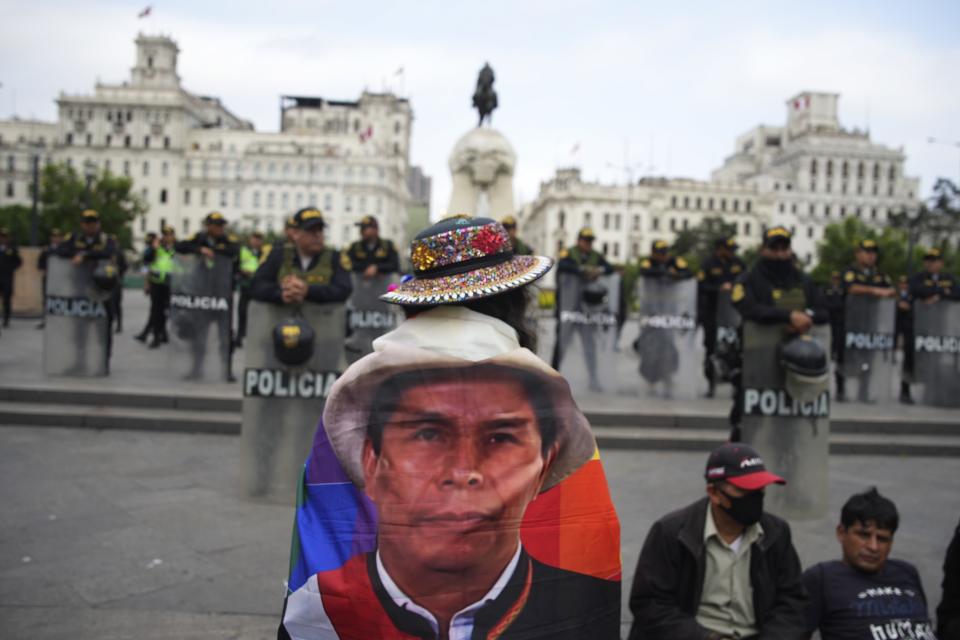 Un manifestante de oposición lleva una bandera con ua foto del destituido presidente Pedro Castillo ante un cordón policial en la plaza de San Martín en el centro de Lima, Perú, el miércoles 19 de julio de 2023. La protesta exige a la presidenta peruana Dina Boluarte un adelanto electoral inmediato, así como justicia por los muertos en las manifestaciones que sucedieron a la destitución de Pedro Castillo como presidente. (AP Foto/Guadalupe Pardo)