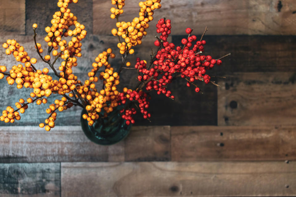 Top view of yellow and orange berries in blue jar on rustic wood background with copy space. (Getty Images)