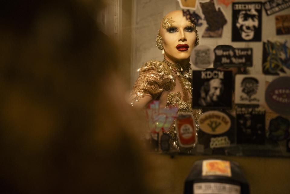 Sasha Velour posing in a mirror mostly covered by stickers in Tennessee in 'We're Here'  