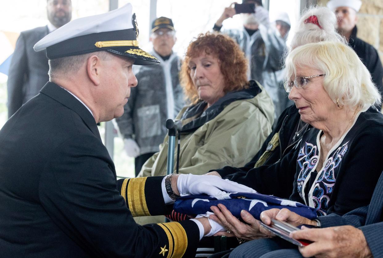 U.S. Navy Rear Adm. Ken Blackmon, left, presents Lynn Such, cousin of fallen World War II Fireman 1st Class Walter Schleiter, of Massillon, an honorary flag during the sailor's military funeral at the National Cemeteries of the Alleghanies in Bridgeville, Pennsylvania. Around 100 people attended the ceremony, which included full military honors for Schleiter.