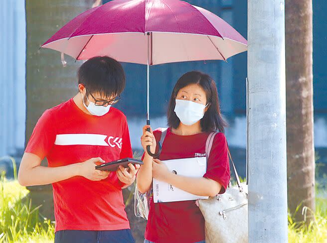 大學分科測驗11日首次登場，由於天氣炎熱，考生最後衝刺時，家長在旁撐著傘遮陽。（陳君瑋攝）