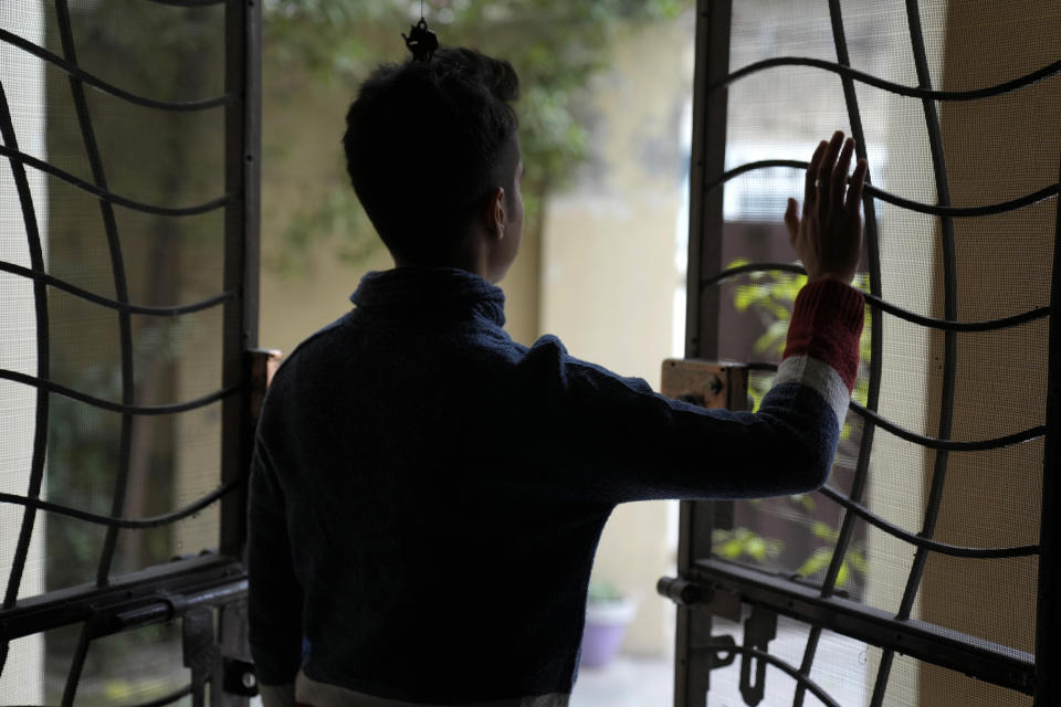 Pakistani trans man Aman, who asked not be identifiable in the photo, looks out at his home after an interview with The Associated Press, in Lahore, Pakistan, Friday, Dec. 2, 2022. Trans people are considered outcasts by many in Pakistan, despite some progress with a law protecting their rights and court rulings that allow them to choose a gender that is neither male nor female. But the struggle for acceptance and inclusion is harder for Pakistan's trans men, who say they lack the same level of support and visibility as trans women, who are in public office, in films, and on TV. (AP Photo/K.M. Chaudary)