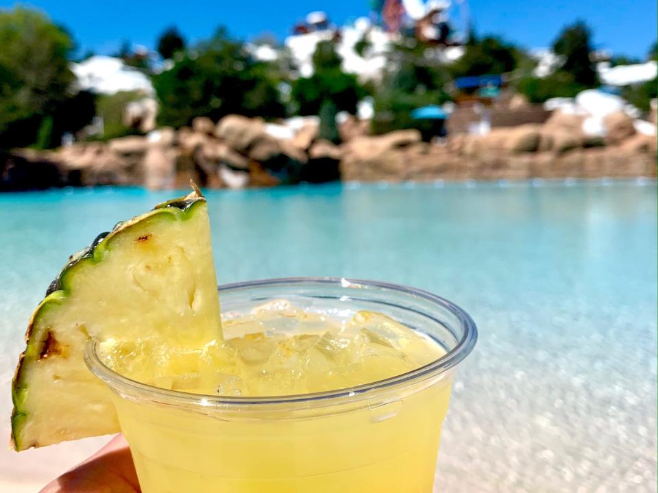 hand holding cocktail next to a pool at blizzard beach water park disney world