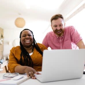 Man and woman looking at laptop at desk in home office