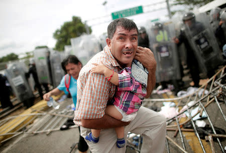 A Honduran migrant protects his child after fellow migrants, part of a caravan trying to reach the U.S., stormed a border checkpoint in Guatemala, in Ciudad Hidalgo, Mexico, October 19, 2018. REUTERS/Ueslei Marcelino/File photo