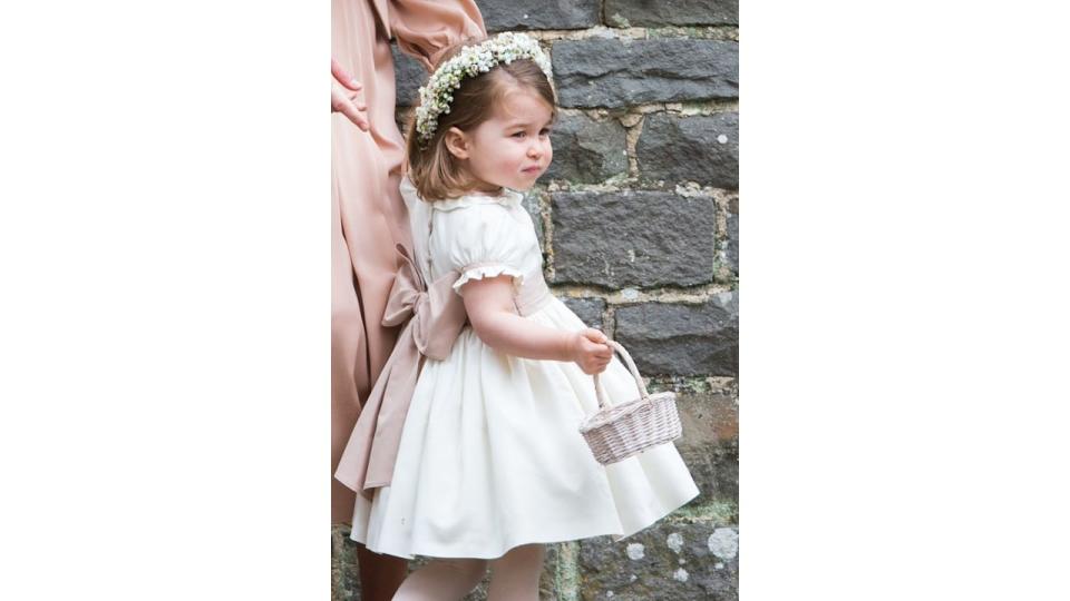 Princess Charlotte wearing a white flower girl dress with bow at the wedding of her auntie Pippa Middleton 2017