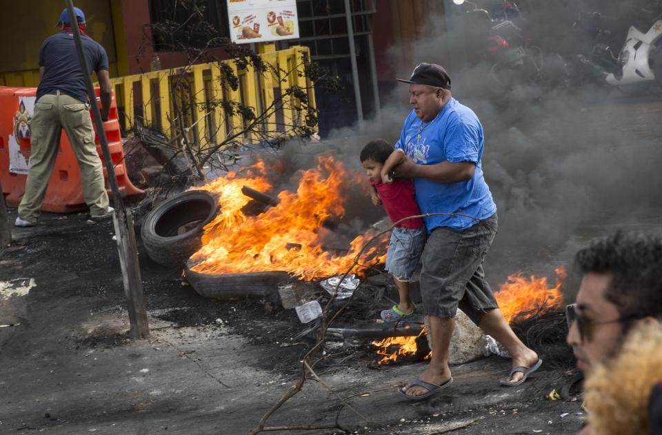 <p>A man carries a boy as they cross a burning barricade erected by supporters of presidential candidate Salvador Nasralla protesting the officials results that have trickled out giving incumbent President Juan Orlando Hernandez a growing lead, in Tegucigalpa, Honduras, Friday, Dec. 1, 2017. (Photo: Rodrigo Abd/AP) </p>