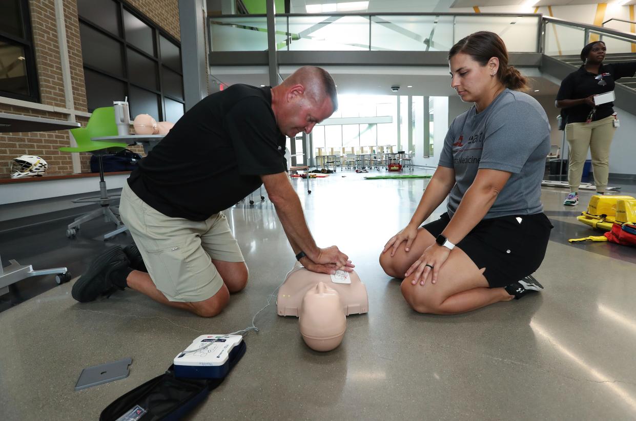 Certified athletic trainers Willie Henson, left, and Taylor Zuberer administer CPR to an unconscious person during an emergency response training session of first responders and athletic trainers at the St. X High School in Louisville, Ky. on July 26, 2023. 