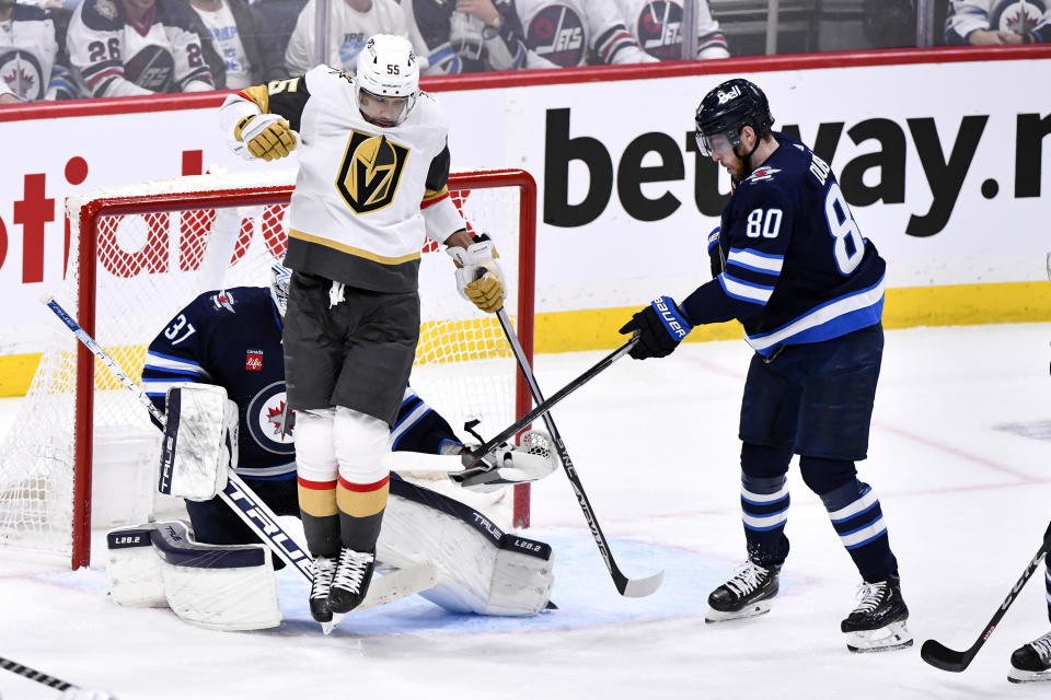 Winnipeg Jets' goaltender Connor Hellebuyck (37) makes a save as Vegas Golden Knights' Keegan Kolesar (55) jumps in front of him as he is defended by Jets' Pierre-Luc Dubois (80) during second-period Game 4 NHL Stanley Cup first-round hockey playoff action in Winnipeg, Manitoba, Monday April 24, 2023. (Fred Greenslade/The Canadian Press via AP)