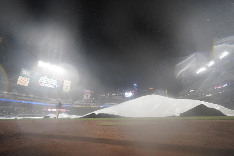 Grounds crew members cover the infield with the tarp during a rain delay for a baseball game between the Minnesota Twins and the San Francisco Giants, Saturday, Aug. 27, 2022, in Minneapolis. (AP Photo/Abbie Parr)
