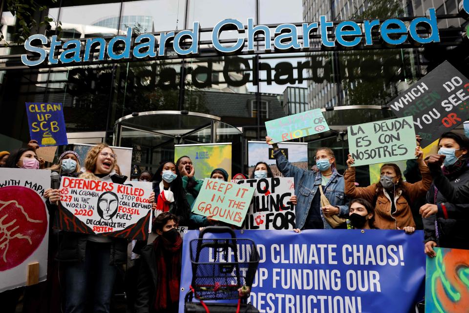 Climate activists hold placards and shout slogans during a demonstration demanding that ‘big finance’ defunds fossil fuels, outside the headquarters of Standard Chartered bank in the City of London (AFP via Getty Images)