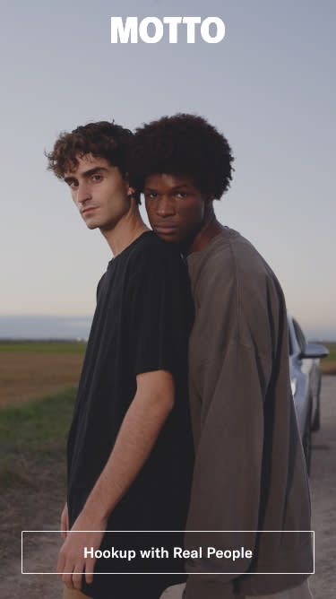 A gay couple standing under the Motto logo. (Motto)