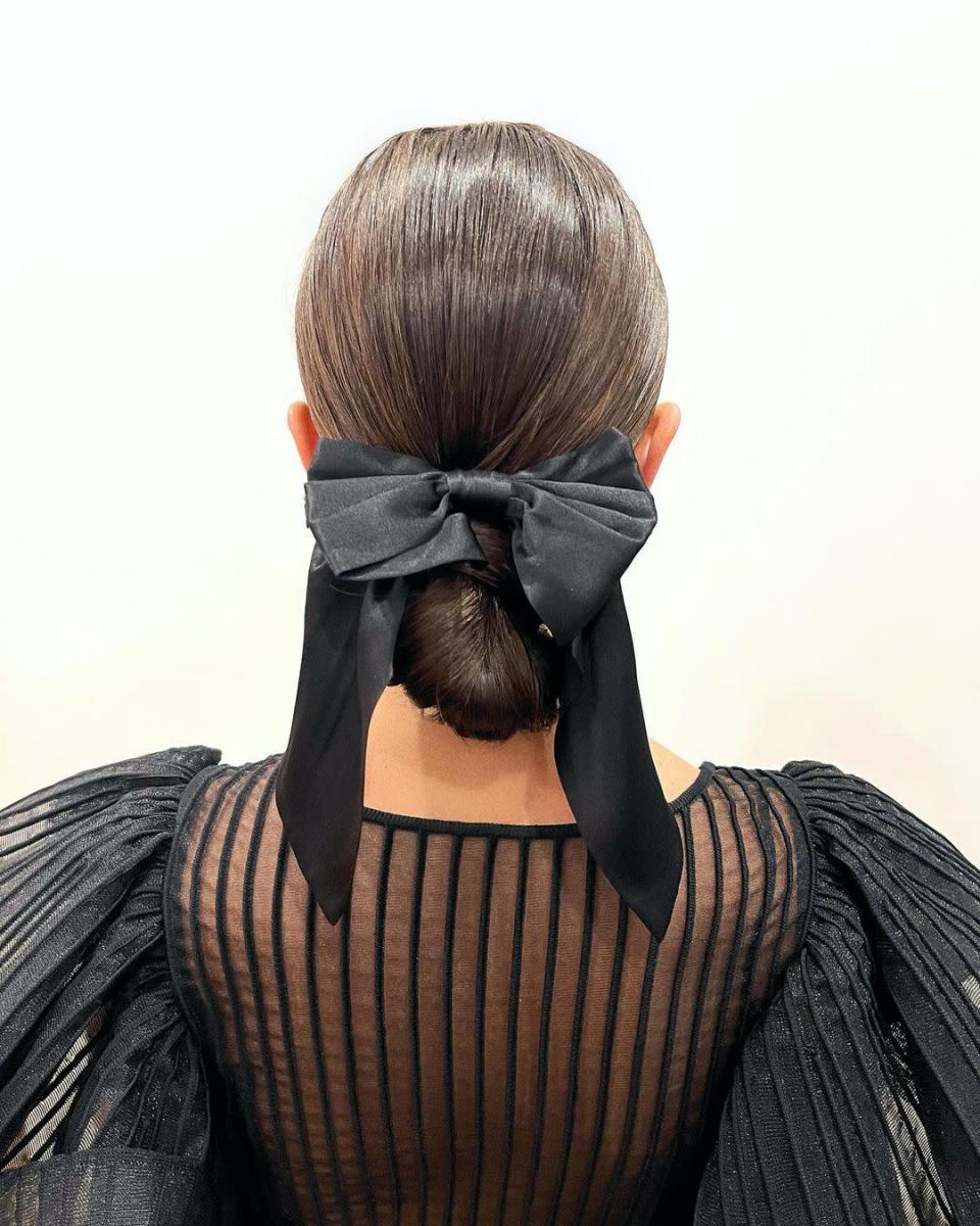To add a celebratory touch to a polished chignon, finish it with a bow. You can grab a satin one as Marjan did here, or give it an evening upgrade with velvet—both Redway and Marjan love this <a href="https://shop-links.co/chEXb0ijDD3" rel="nofollow noopener" target="_blank" data-ylk="slk:PatBO x Tresemmé" class="link ">PatBO x Tresemmé</a> version. For a look this sleek, secure it with a strong-hold gel and a smoothing brush before you head out.