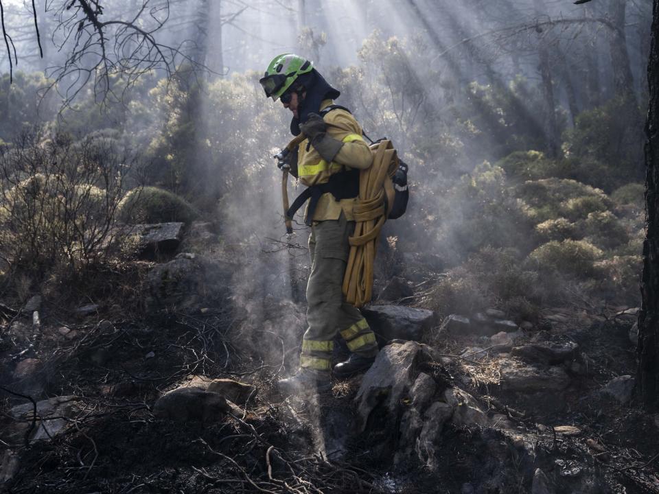 A forest firefighter works extinguishing hot spots in a wildfire near the town of Jubrique, in Malaga province, Spain, Saturday, Sept. 11, 2021. Firefighting crews in southern Spain are waiting for much-needed rainfall expected on Monday that they hope can help extinguish a stubborn mega-fire that has ravaged 7,400 hectares (18,300 acres) in five days and displaced some 3,000 people from their homes. (AP Photo/Pedro Armestre)