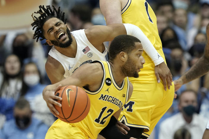 North Carolina guard R.J. Davis collides with Michigan center Hunter Dickinson (1) while guard DeVante' Jones (12) dribbles during the first half of an NCAA college basketball game in Chapel Hill, N.C., Wednesday, Dec. 1, 2021. (AP Photo/Gerry Broome)