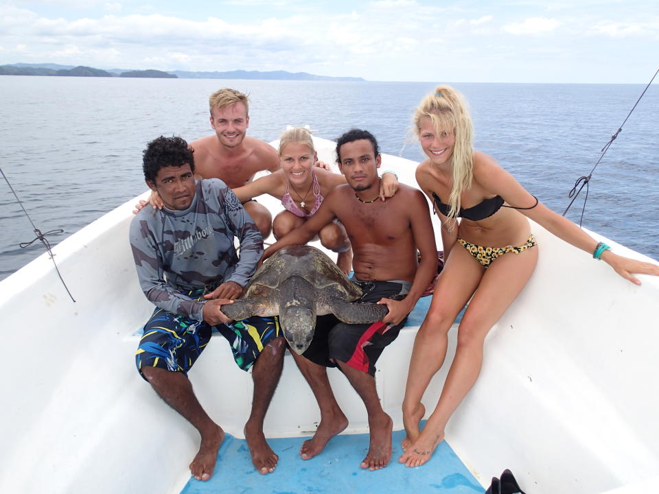 Figgener poses with a sea turtle and members of her research team on their boat in Costa Rica in 2015. L to R: Macdonal Gomez, Daniel Stuart, Christine Figgener, Andrey MacCarthy, and Vee Koleff.