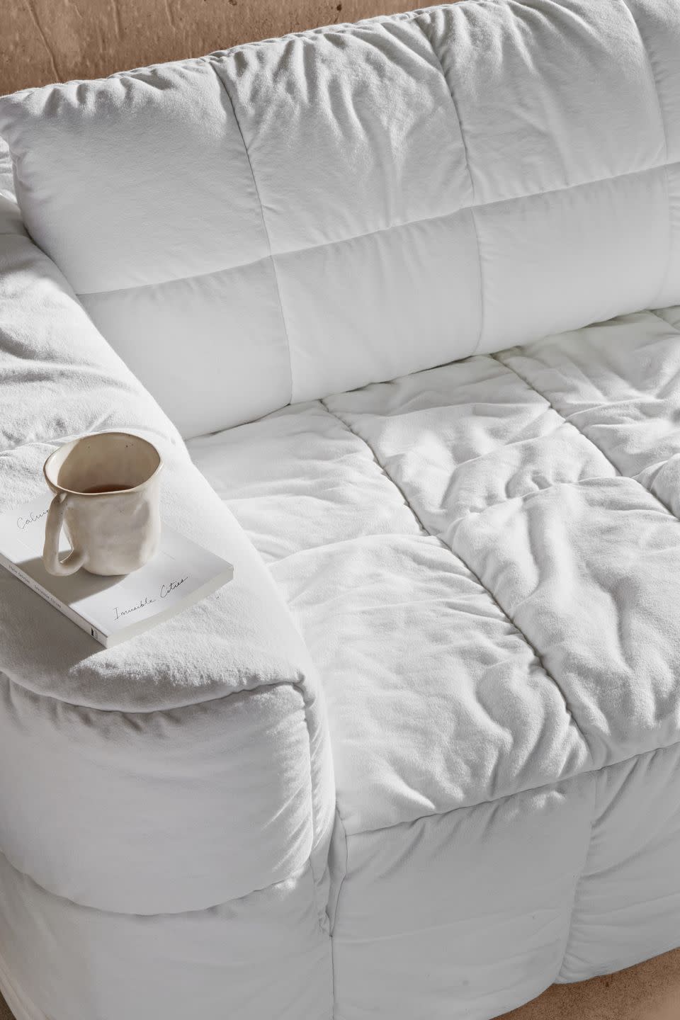 a white pillow with a white pillow and a coffee cup on it