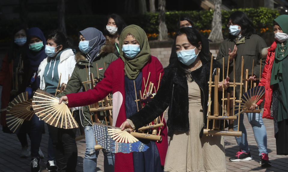 Indonesian migrant workers wear face masks as they play the traditional music instrument "angklung" in Hong Kong, Monday, Jan. 27, 2020. Hong Kong announced it would bar entry to visitors from the mainland province at the center of the outbreak. Travel agencies were ordered to cancel group tours nationwide following a warning the virus's ability to spread was increasing.(AP Photo/Achmad Ibrahim)