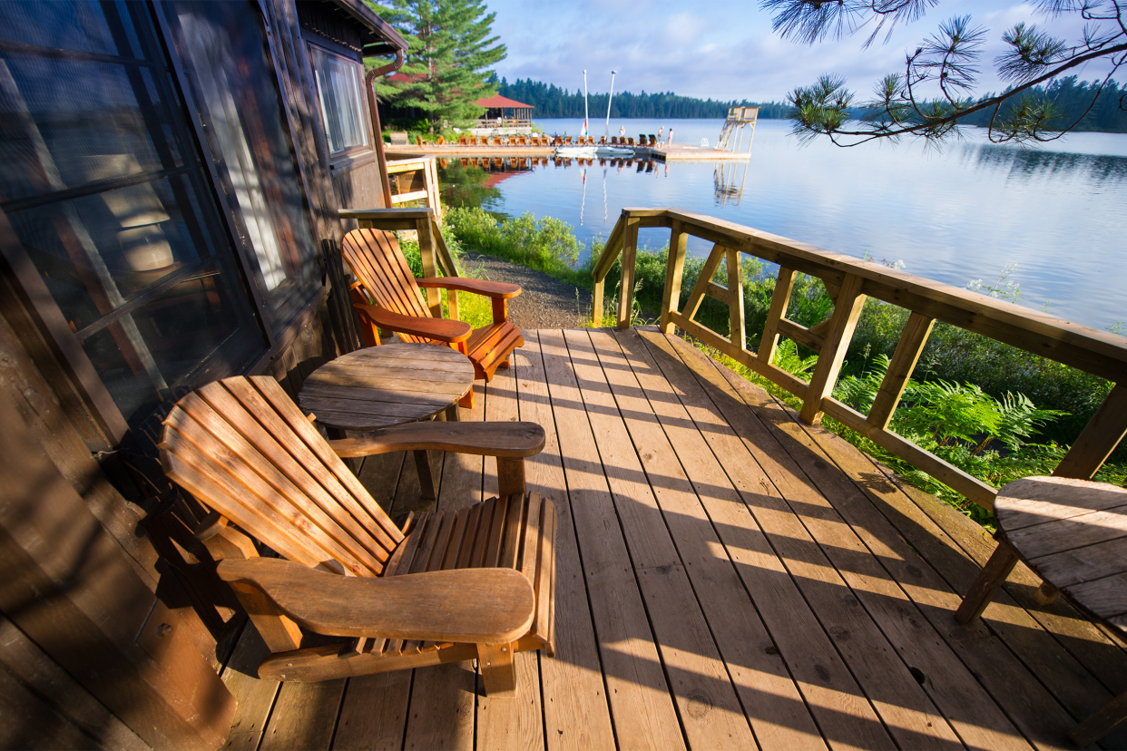 Wooden chairs on the back porch of a lake house