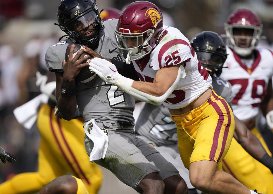 Colorado quarterback Shedeur Sanders, left, is stopped by Southern California linebacker Tackett Curtis (25) in the second half of an NCAA college football game Saturday, Sept. 30, 2023, in Boulder, Colo. (AP Photo/David Zalubowski)