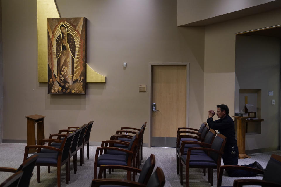 Maintenance technician Richard Martinez prays in an empty chapel at Providence Holy Cross Medical Center in the Mission Hills section of Los Angeles Saturday, Jan. 9, 2021. Martinez said he prayed for all the patients and for the hospital to continue to have its doors open to allow as many patients as possible. (AP Photo/Jae C. Hong)