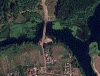 A satellite image of a strategic Russian bridge that has been hit. There are black spots on the bridge.