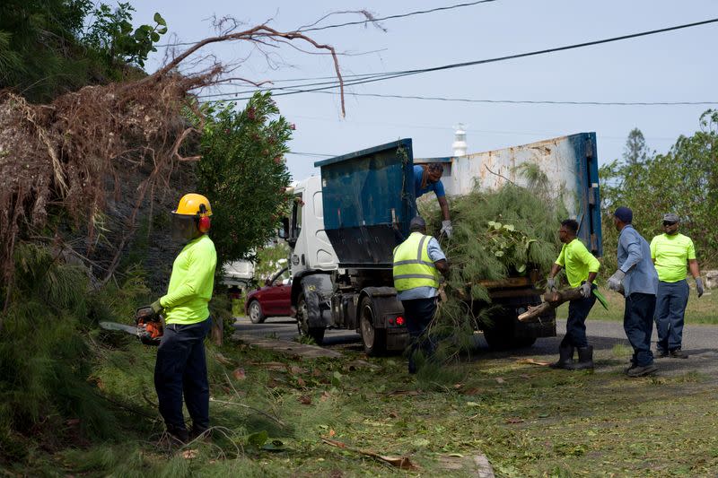 A work crew clears debris after high winds from Hurricane Fiona hit the south shore of Bermuda