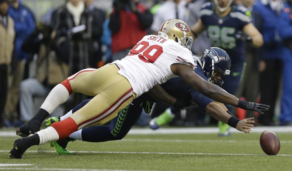 Seattle Seahawks' Russell Wilson and San Francisco 49ers' Aldon Smith go after Wilson's fumble on the first play of the first half of the NFL football NFC Championship game Sunday, Jan. 19, 2014, in Seattle. The 49ers recovered the ball. (AP Photo/Marcio Jose Sanchez)