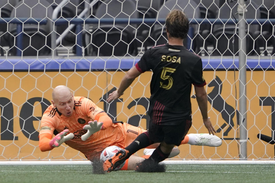 Atlanta United goalkeeper Brad Guzan, left, makes a stop as midfielder Santiago Sosa (5) pulls up from moving in to defend during the first half of an MLS soccer match against the Seattle Sounders, Sunday, May 23, 2021, in Seattle. (AP Photo/Ted S. Warren)