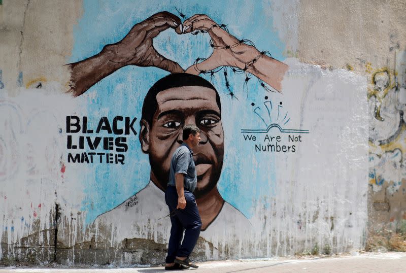 A Palestinian man walks past a mural depicting George Floyd, in Gaza City