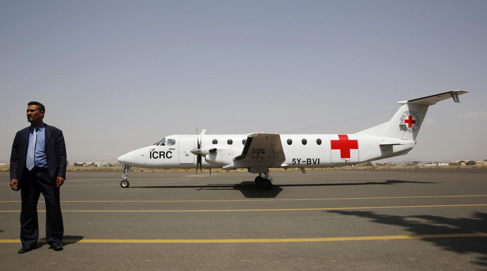 FILE - In this Aug. 8, 2015 file photo, a Yemeni airport security official stands by a plane of the International Committee of the Red Cross on the tarmac of the international airport in Sanaa, Yemen. The Norwegian Refugee Council and CARE have slammed the Saudi-led coalition for its closure of the airport in Yemen's capital, saying this has prevented thousands of sick civilians from traveling abroad for urgent medical treatment, saying the Sanaa airport's three-year closure has amounted to a "death sentence" for many sick Yemenis. The two aid groups appealed late Monday, Aug 5, 2019 on Yemen's warring parties to come to an agreement to reopen the airport for commercial flights to "alleviate humanitarian suffering caused by the closure." (AP Photo/Hani Mohammed, File)