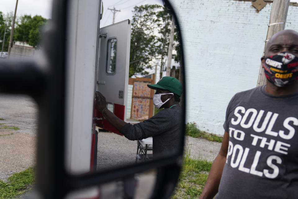 A man is reflected in a side mirror of a mobile help unit as he receives medical supplies during a harm reduction effort in the city in St. Louis on Friday, May 21, 2021. (AP Photo/Brynn Anderson)