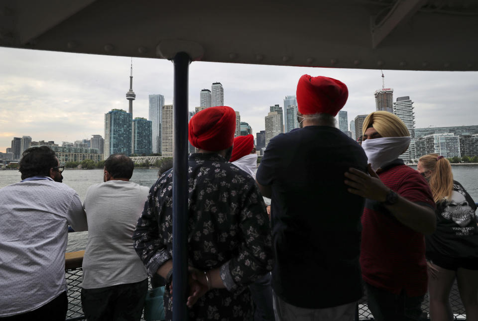 People look at the city skyline on a ferry coming back from Centre Island to Toronto, Canada, Saturday, July 17, 2021. With nearly 70% of its adult population receiving at least one dose of a COVID-19 vaccine, Canada has the world's highest vaccination rate and is now moving on to immunize children, who are at far lower risk of coronavirus complications and death. (AP Photo/Kamran Jebreili)