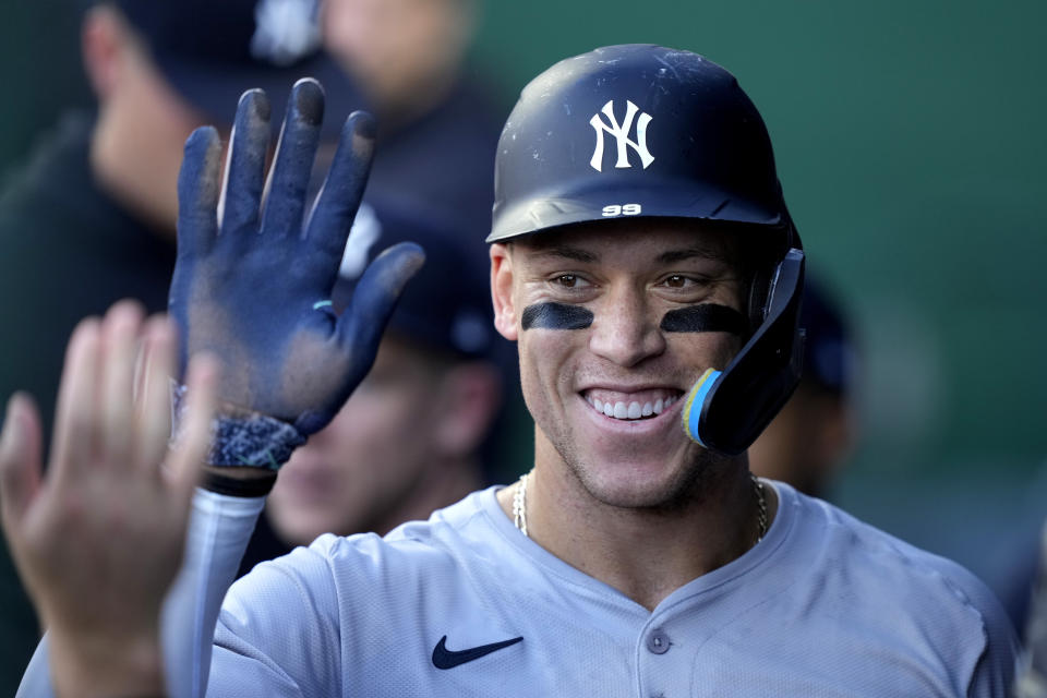 New York Yankees' Aaron Judge celebrates in the dugout after scoring on sacrifice fly hit by Anthony Rizzo during the first inning of a baseball game against the Kansas City Royals Wednesday, June 12, 2024, in Kansas City, Mo. (AP Photo/Charlie Riedel)