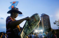 A Workers' Party supporter reads the papers while waiting for the first speaker to start at the rally in Hougang on Thursday, 28 April. (Yahoo! photo/ Liyana Low) 