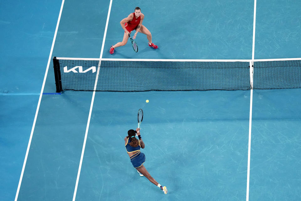 Coco Gauff, bottom, of the U.S. plays a backhand return to Aryna Sabalenka of Belarus during their semifinal match at the Australian Open tennis championships at Melbourne Park, Melbourne, Australia, Thursday, Jan. 25, 2024. (AP Photo/Louise Delmotte)