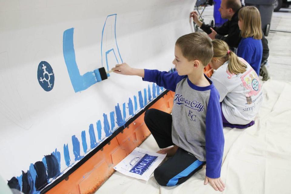 Christopher Childs, 8, helps paint his sister Katie Childs’ design on a snow plow as part of the snOlathe art contest.