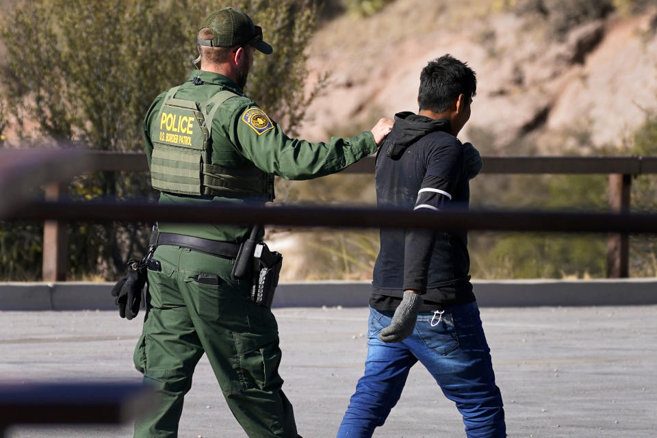 A Customs and Border Patrol agent detains a migrant atop Montezuma's Pass in Coronado National Memorial, Wednesday, Dec. 9, 2020, in Hereford, Ariz. Construction of the border wall, mostly in government owned wildlife refuges and Indigenous territory, has led to environmental damage and the scarring of unique desert and mountain landscapes that conservationists fear could be irreversible. (AP Photo/Matt York)