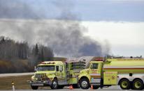 Smoke rises in the distance as firefighters block a highway leading to an area where a train derailed, in the small town of Gainford, Alberta west of Edmonton October 19, 2013. The train carrying crude oil and liquefied petroleum gas derailed west of Edmonton, Alberta, causing an explosion and fire but no injuries, Canadian National Railway said on Saturday. REUTERS/Dan Riedlhuber (CANADA - Tags: DISASTER TRANSPORT)