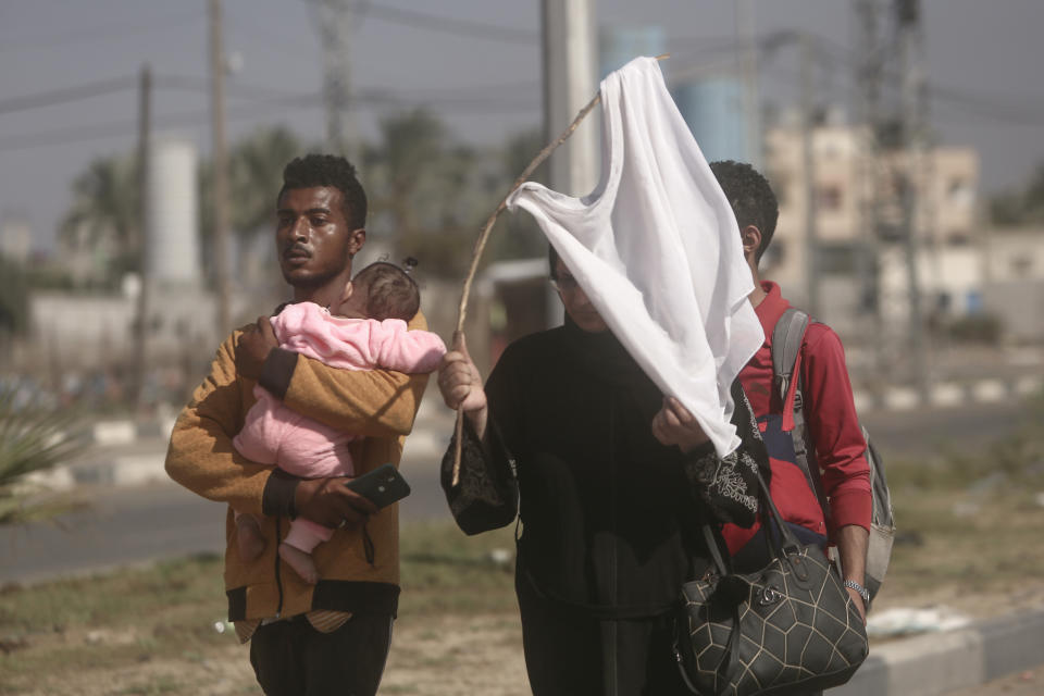 A woman holds-up a white T-shirt trying to prevent being shot, as Palestinians flee Gaza City to the southern Gaza Strip on Salah al-Din street in Bureij, Tuesday, Nov. 7, 2023. (AP Photo/Mohammed Dahman)