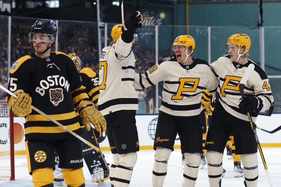 Pittsburgh Penguins' Kasperi Kapanen, second from right, celebrates after his goal with teammates Jeff Carter, second from left, and Danton Heinen (43) behind Boston Bruins' Connor Clifton (75) during the second period of the NHL Winter Classic hockey game, Monday, Jan. 2, 2023, at Fenway Park in Boston. (AP Photo/Michael Dwyer)