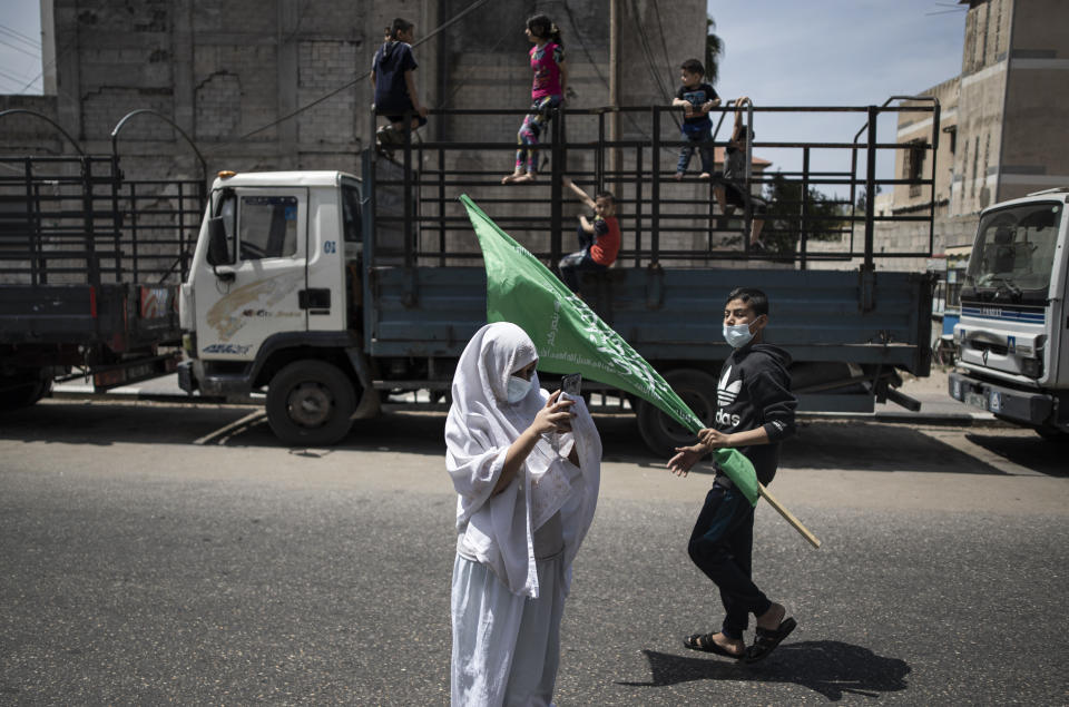 Palestinian children swing on the back of a truck as a young girl uses a mobile phone to photograph Hamas supporters protest in solidarity with Muslim worshippers in Jerusalem, in Gaza City, Friday, April. 23, 2021. (AP Photo/Khalil Hamra)