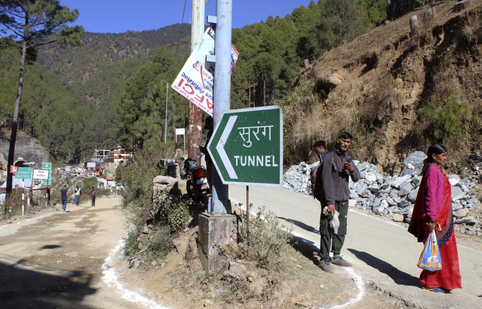 people walk near the site of an under-construction road tunnel that collapsed trapping 41 workers in Silkyara in the northern Indian state of Uttarakhand, Wednesday, Nov. 22, 2023. The workers have been trapped for over a week, as rescuers work on an alternate plan of digging toward them vertically. (AP Photo)