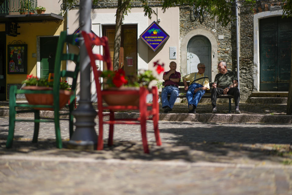 Men sit on a bench on the "Corso Giuseppe Garibaldi" main street of Serrastretta, southern Italy, Friday, July 8, 2022. From a rustic, tiny synagogue she fashioned from her family's ancestral home in this mountain village, American rabbi Aiello is keeping a promise made to her Italian-born father: to reconnect people in this southern region of Calabria to their Jewish roots, links nearly severed five centuries ago when the Inquisition forced Jews to convert to Christianity. (AP Photo/Andrew Medichini)