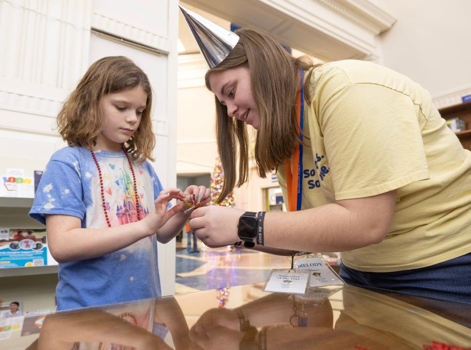 Massillon Public Library volunteer Melody Anderson helps Makenzie Ohman, 8, make a "firework ring" at the Massillon Public Library's Noon Year's Eve Party.