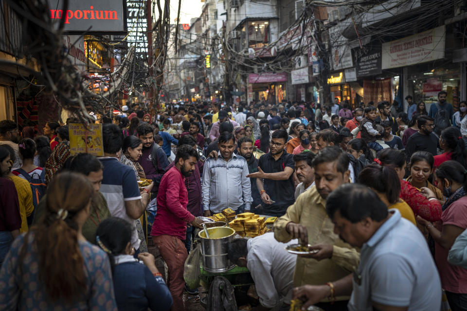 People eat street food as shoppers crowd a market in New Delhi, India, in a Nov. 12, 2022 file photo. / Credit: Altaf Qadri/AP