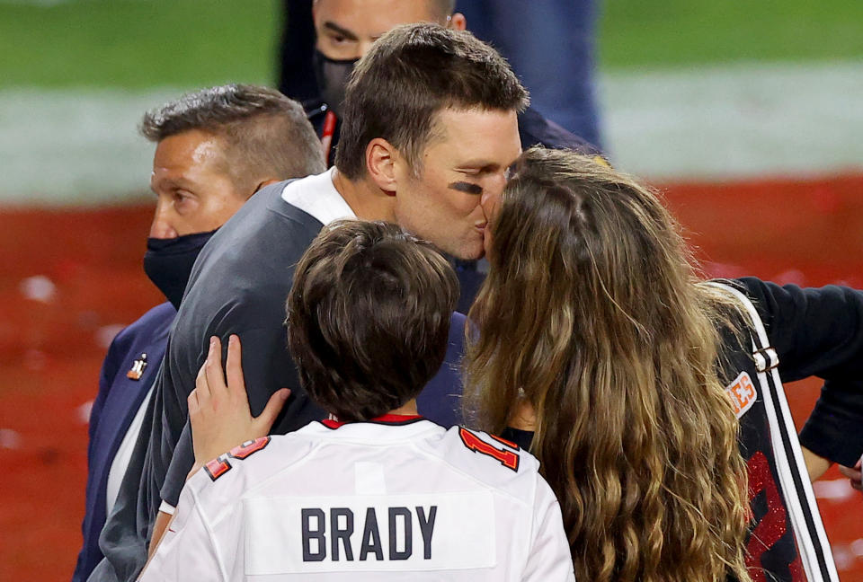 Tom and Gizelle kissing on the field after a game